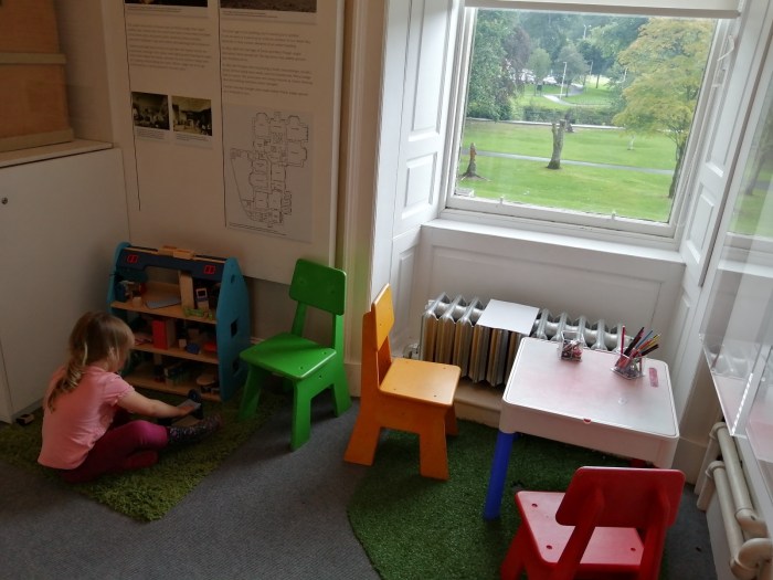 Girl playing dolls house small table and chairs