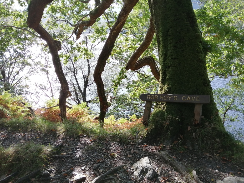 west highland way, scotland, trees, rob roys cave, sign