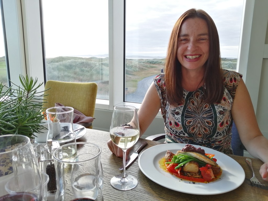 lady smiling, wine, food, view golf course, machrie hotel, islay, scotland