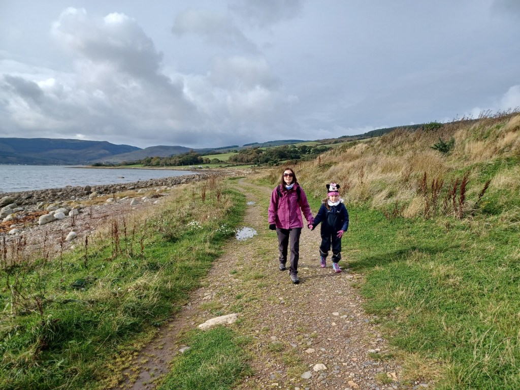 lady and girl walking, open water, path, beach, arran