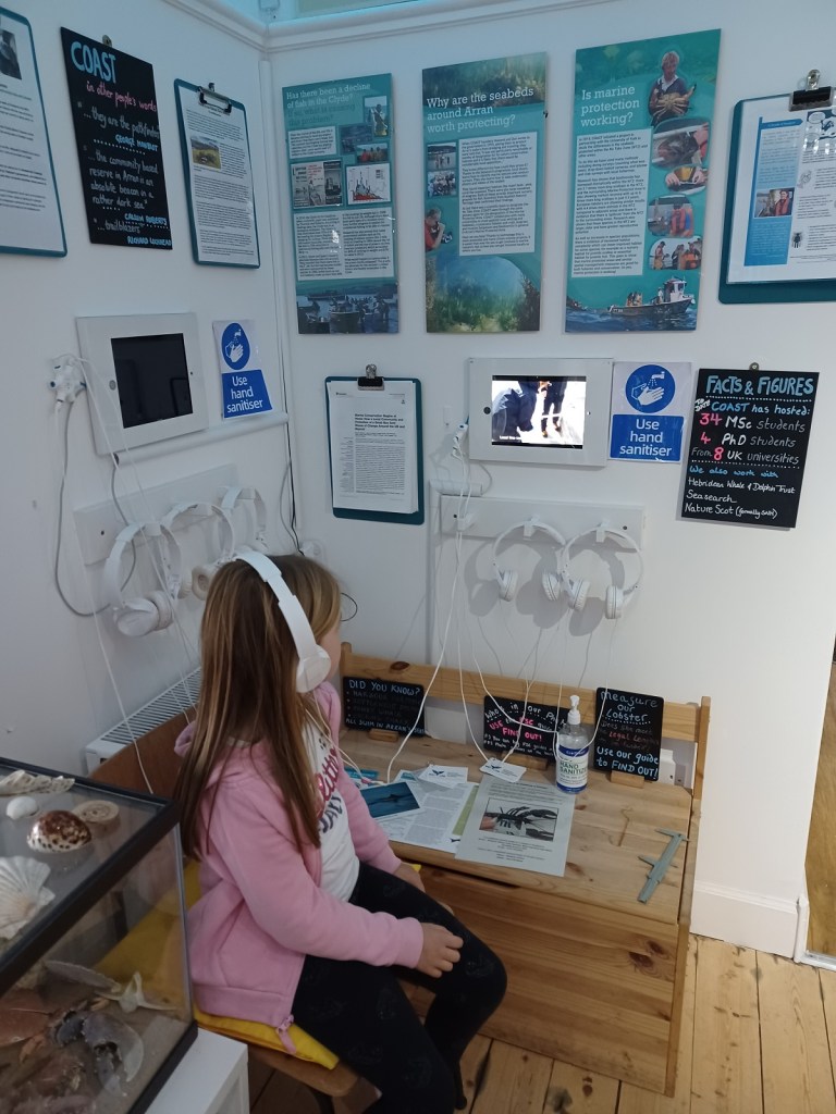 girl with headphones, girl watching tablet, COAST Centre, Lamlash, Isle of Arran, girl in pink cardigan 