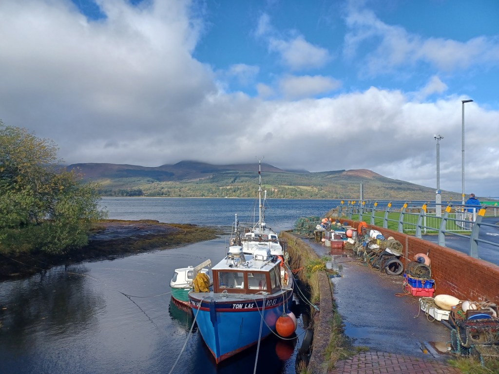 fishing boat, inlet, blue skies, cloudy skies, mountains covered in clouds